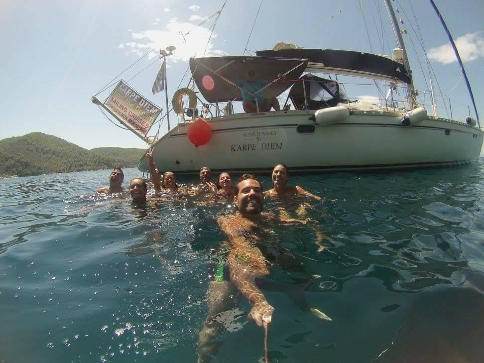 A happy group celebrating in the sea behind an anchored Carpe Diem yacht